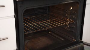An empty oven with the door open, preheating with the rack in the center position
