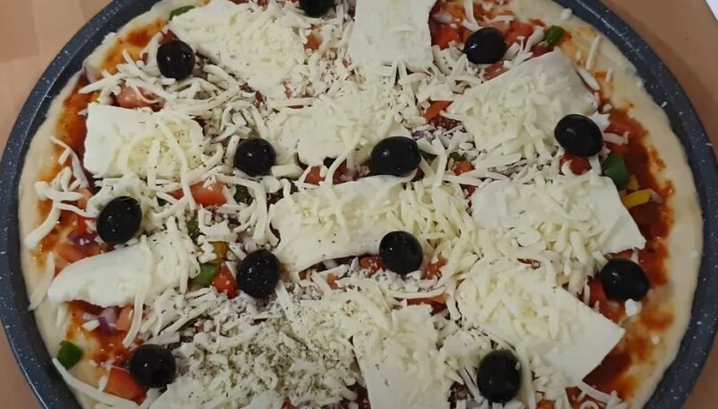 A pizza, generously topped with mozzarella cheese, olives, and vegetables