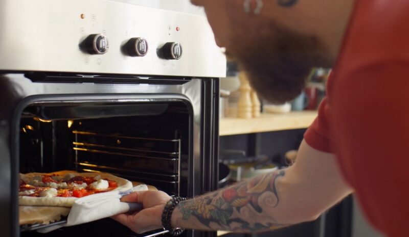 Man puts pizza in the oven