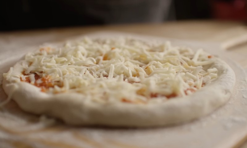 A cheese-topped pizza resting on a wooden board