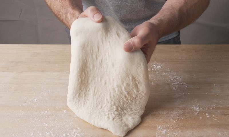 A man kneads dough on a wooden table