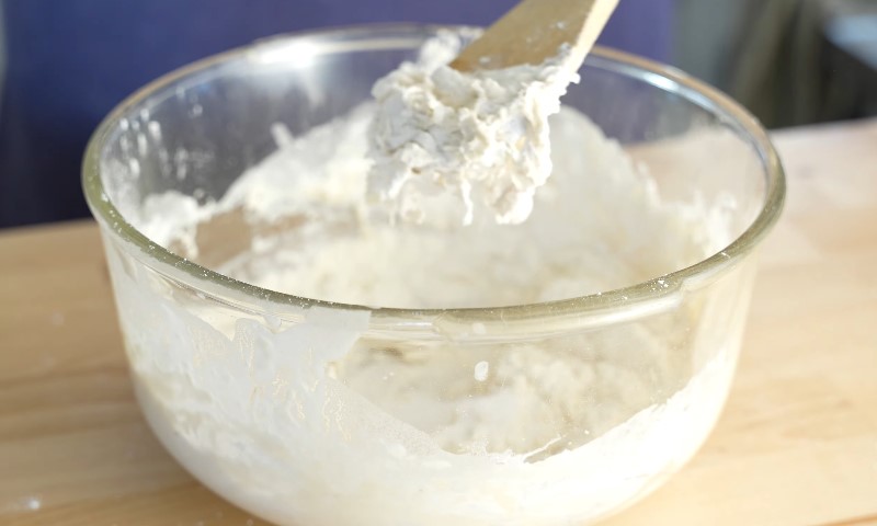A bowl of white flour with a wooden spoon resting inside, ready for baking