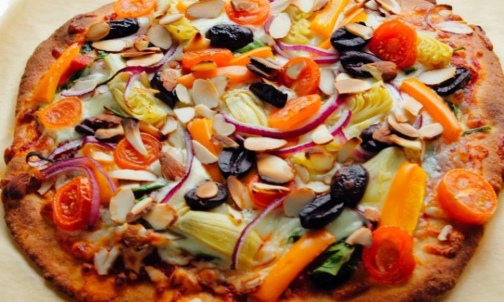 A freshly baked pizza topped with colorful vegetables and melted cheese on a silver baking sheet