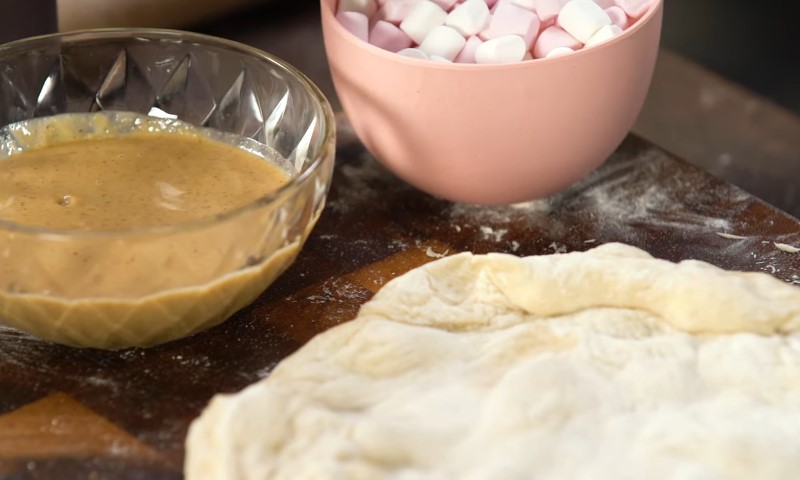 A bowl of fluffy white marshmallows next to a bowl of creamy peanut butter