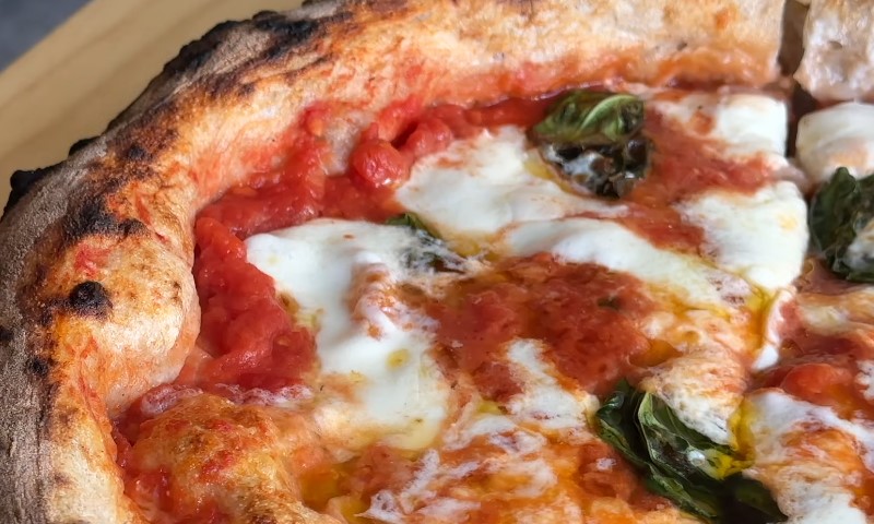 Close-up of a pizza topped with melted cheese and fresh basil leaves